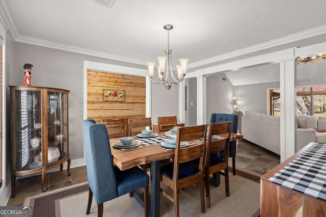 dining room with decorative columns, wooden walls, a chandelier, and crown molding