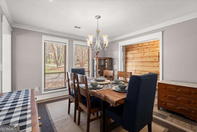 dining area with visible vents, a notable chandelier, and ornamental molding