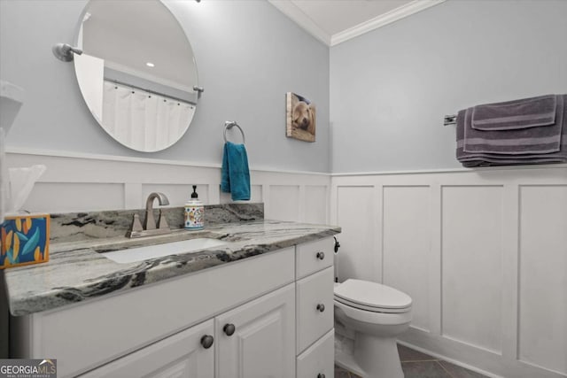 full bathroom featuring tile patterned floors, toilet, ornamental molding, wainscoting, and vanity