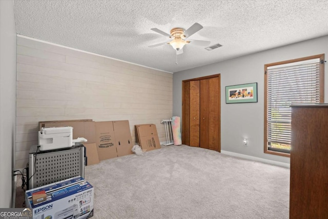 interior space featuring visible vents, a textured ceiling, ceiling fan, and carpet flooring