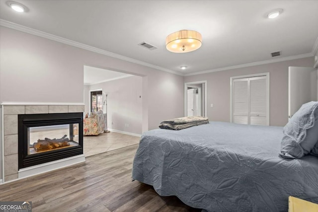 bedroom featuring a closet, visible vents, crown molding, and wood finished floors