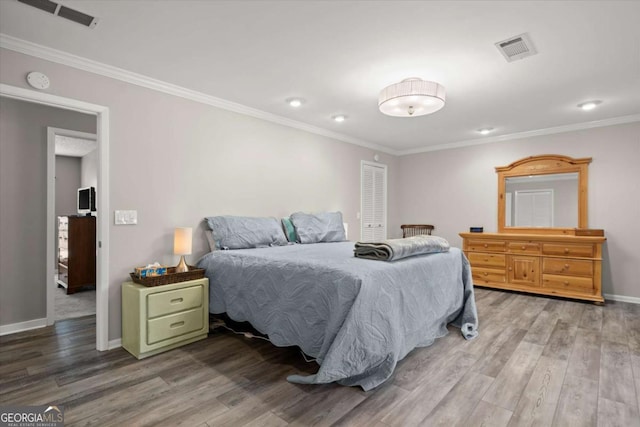 bedroom featuring crown molding, wood finished floors, visible vents, and baseboards