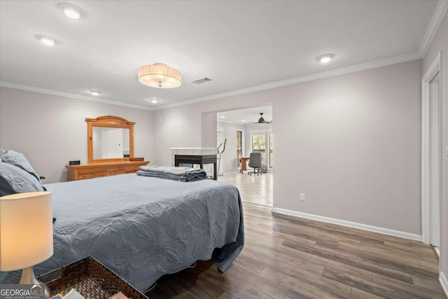 bedroom with ornamental molding, wood finished floors, visible vents, and baseboards