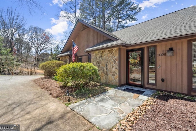 property entrance with stone siding and roof with shingles