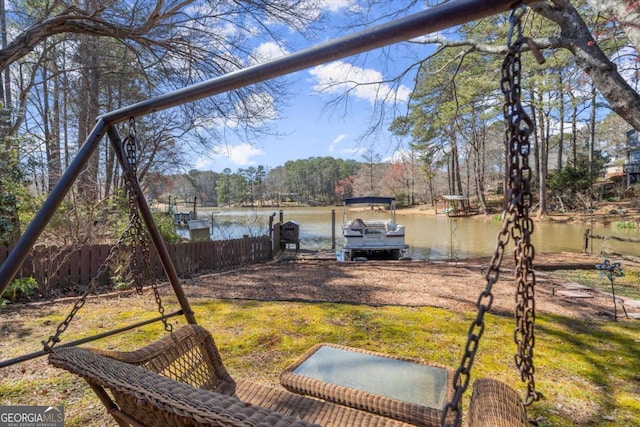 view of yard with fence, a dock, and a water view