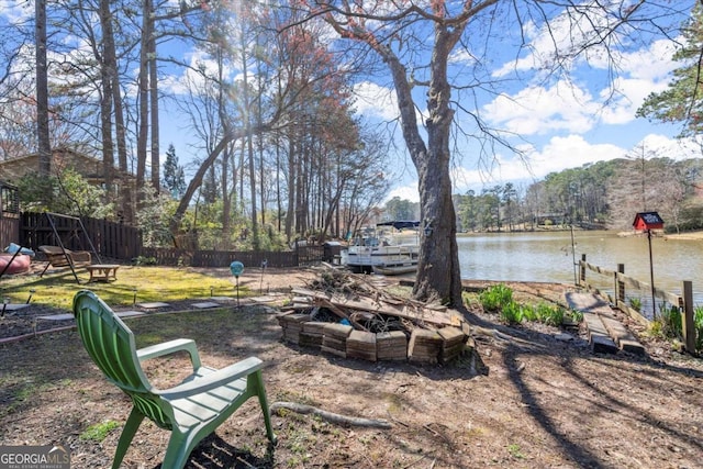 view of yard with a fire pit, fence, a water view, and a boat dock