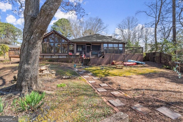 rear view of house featuring a deck and fence