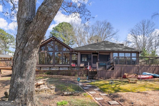 rear view of house with stairway, a wooden deck, and a sunroom