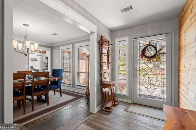 doorway featuring a notable chandelier, visible vents, plenty of natural light, and stone tile flooring