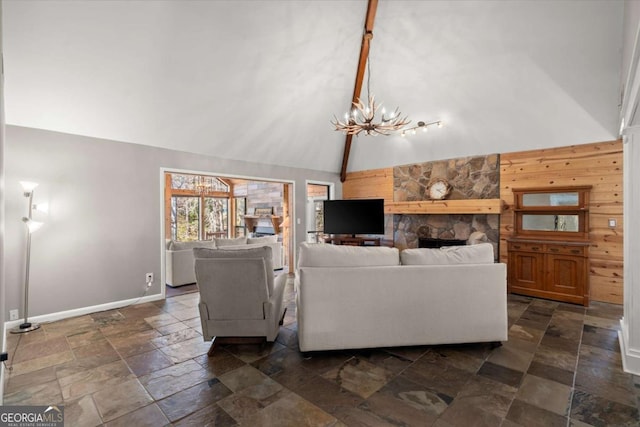 living area featuring wooden walls, baseboards, a chandelier, stone tile floors, and high vaulted ceiling