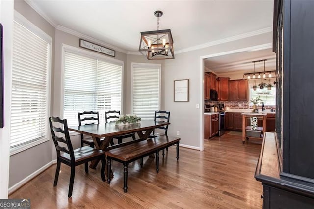 dining room with light wood finished floors, baseboards, an inviting chandelier, and ornamental molding