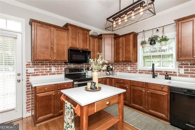 kitchen with a sink, light wood-type flooring, black appliances, and crown molding