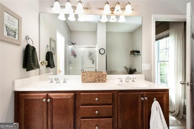 full bath featuring double vanity, a stall shower, and a sink