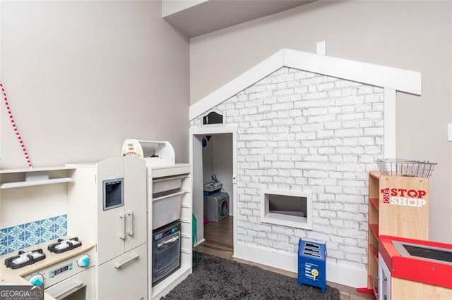 interior space with white range with gas cooktop, brick wall, and stainless steel oven