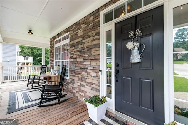 view of exterior entry with covered porch and stone siding