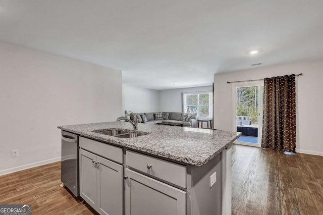 kitchen featuring dark wood-type flooring, open floor plan, dishwasher, an island with sink, and a sink