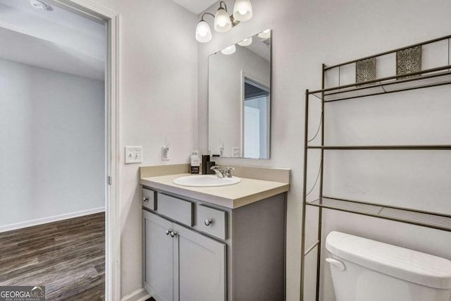 bathroom featuring toilet, vanity, baseboards, and wood finished floors