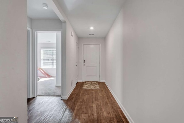 hallway featuring visible vents, wood finished floors, and baseboards