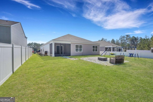 back of house featuring a lawn, a fenced backyard, and a sunroom