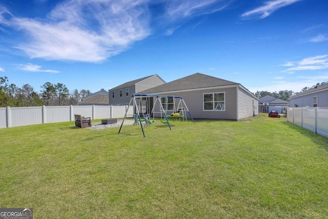 back of house with a fenced backyard, a playground, and a yard