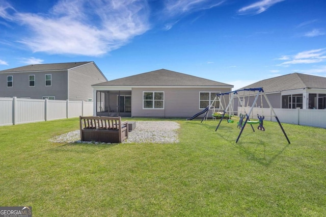 rear view of house with a lawn, a playground, a fenced backyard, and a sunroom