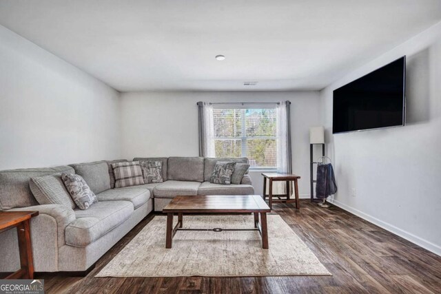 living room featuring visible vents, baseboards, and wood finished floors