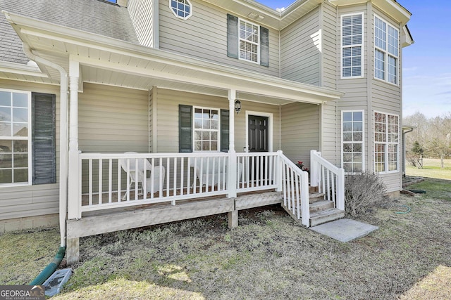 doorway to property with covered porch and a shingled roof