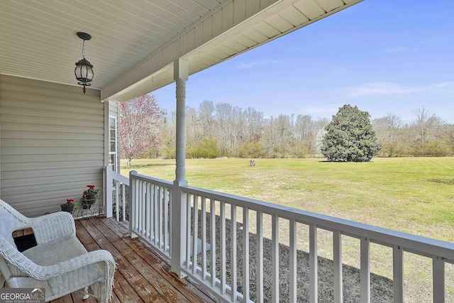 wooden deck featuring covered porch and a lawn