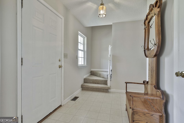 foyer with light tile patterned floors, visible vents, a textured ceiling, and baseboards