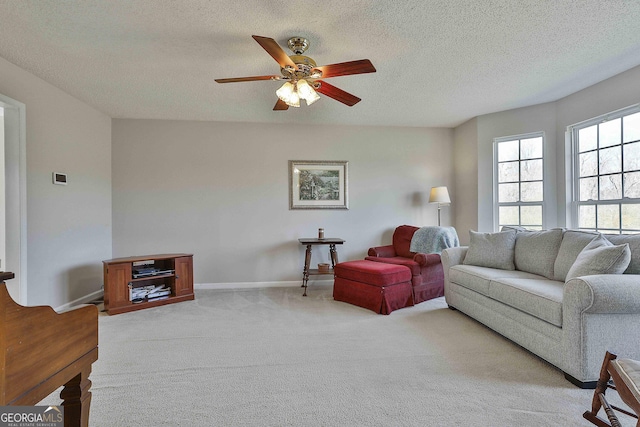 living room with baseboards, light colored carpet, a textured ceiling, and a ceiling fan