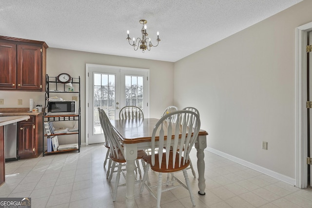 dining room featuring a textured ceiling, french doors, light tile patterned flooring, baseboards, and a chandelier