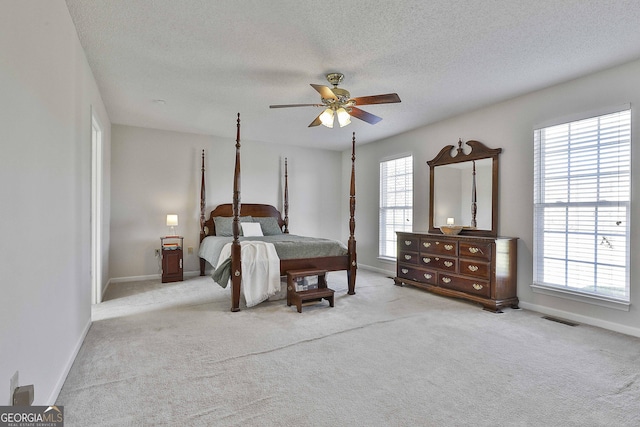 carpeted bedroom featuring visible vents, multiple windows, a textured ceiling, and baseboards