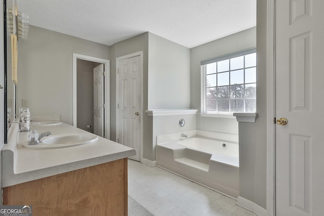 full bath with baseboards, double vanity, a bath, a textured ceiling, and a sink