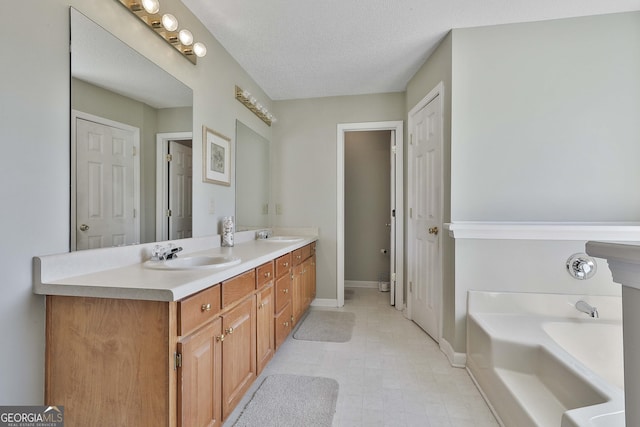 full bath featuring a sink, a garden tub, double vanity, and a textured ceiling