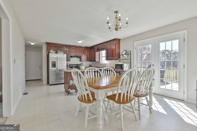 dining area featuring a notable chandelier, french doors, baseboards, and a textured ceiling