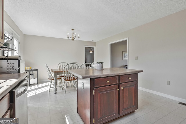 kitchen with baseboards, a kitchen island, a textured ceiling, stainless steel dishwasher, and a chandelier