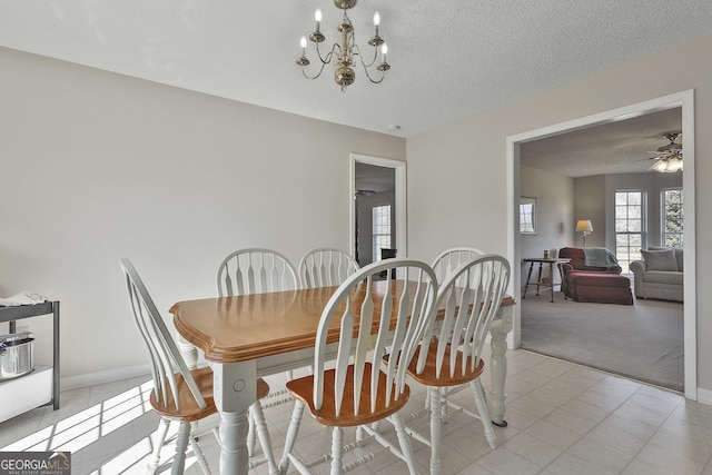 dining room with light carpet, ceiling fan with notable chandelier, a textured ceiling, and baseboards