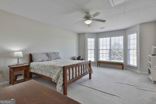 carpeted bedroom featuring visible vents, a textured ceiling, baseboards, attic access, and ceiling fan