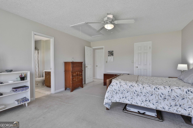 bedroom featuring ensuite bathroom, a textured ceiling, light colored carpet, attic access, and ceiling fan