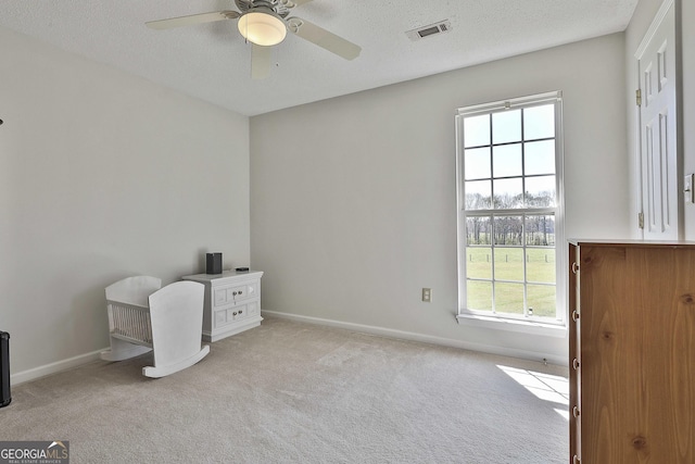 unfurnished office with visible vents, a ceiling fan, a textured ceiling, carpet floors, and baseboards