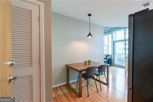 dining room with visible vents, light wood-style flooring, a wall of windows, and baseboards