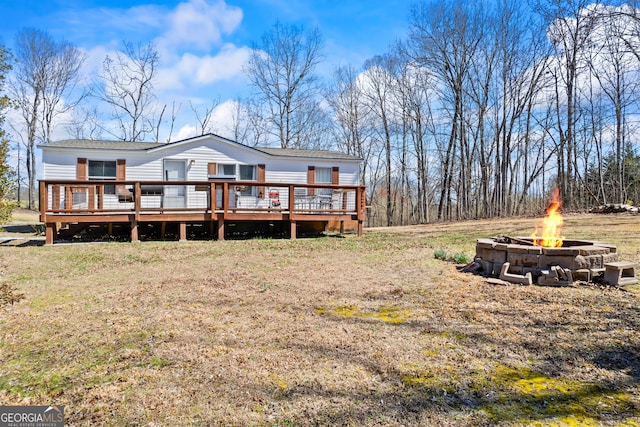 back of house with a wooden deck and a fire pit