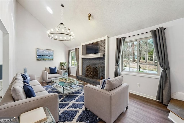 living area with baseboards, a fireplace, an inviting chandelier, wood finished floors, and a textured ceiling