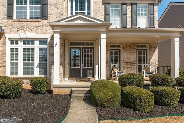 property entrance with a porch and brick siding