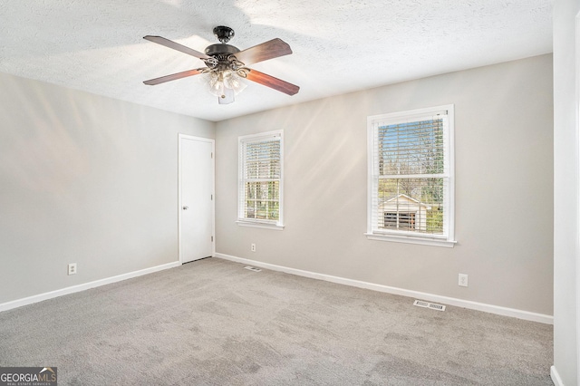 carpeted spare room featuring visible vents, a textured ceiling, and baseboards