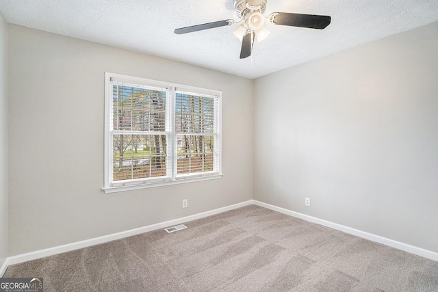 carpeted empty room featuring baseboards, visible vents, and a textured ceiling