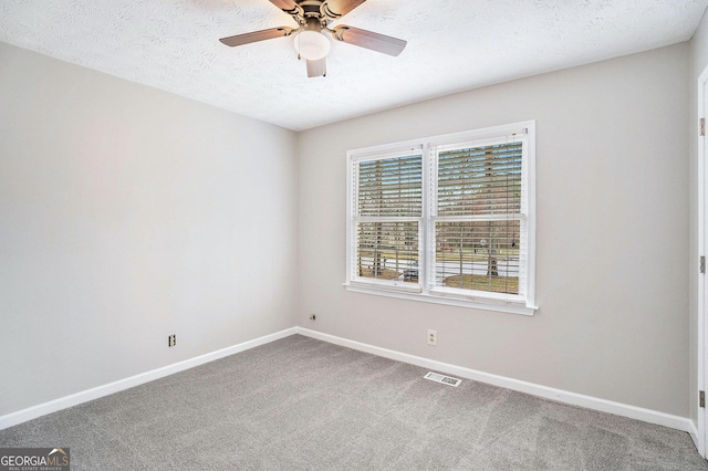 carpeted spare room featuring visible vents, ceiling fan, a textured ceiling, and baseboards