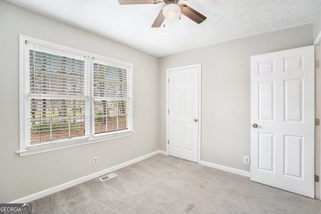 unfurnished bedroom with visible vents, a ceiling fan, a textured ceiling, carpet, and baseboards