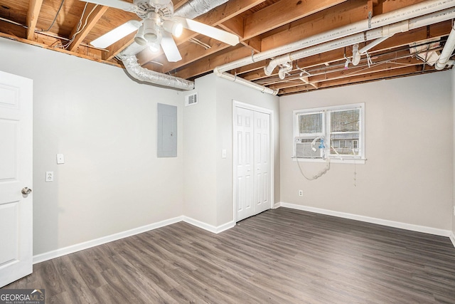 basement featuring electric panel, baseboards, and dark wood-style flooring