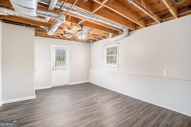 below grade area with baseboards, plenty of natural light, and dark wood-style flooring